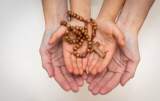 Adult and child hands holding rosary beads